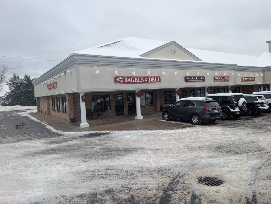 Storefront of Miller Place Bagels and Deli. Snow surrounds the modern store front
