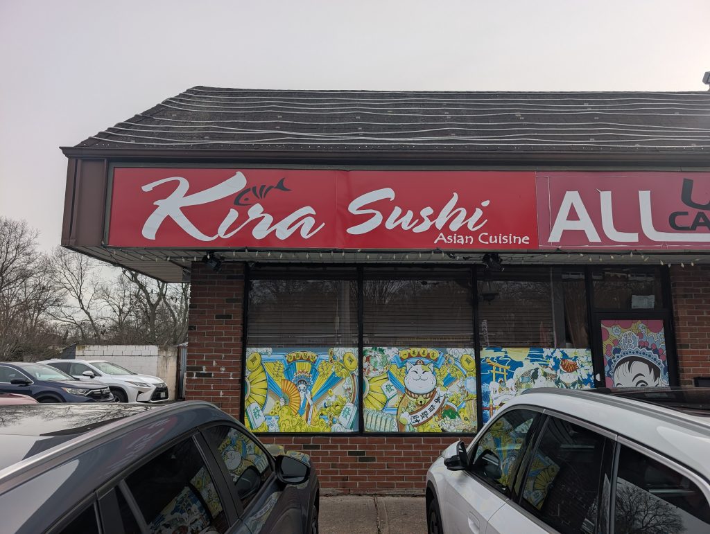 Exterior view of Kira Sushi Asian Cuisine restaurant in Lake Ronkonkoma, New York, featuring a red sign and colorful window murals of a Maneki-neko (lucky cat).