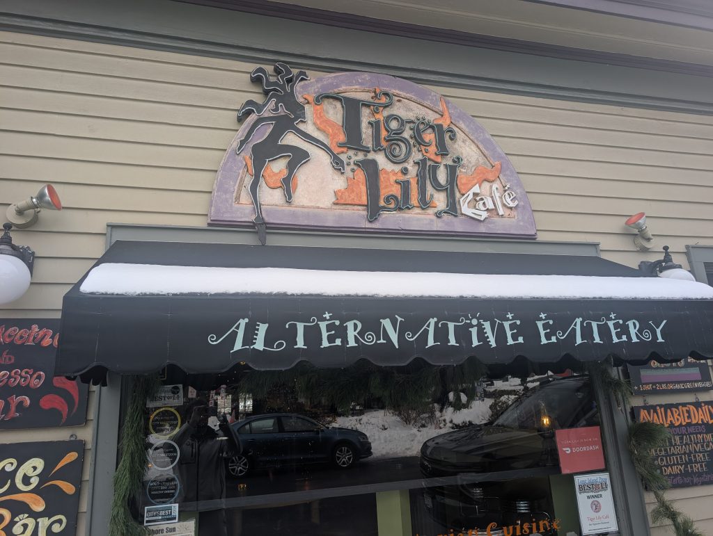 tiger lily cafe storefront with a purple, orange and black medusa art logo.