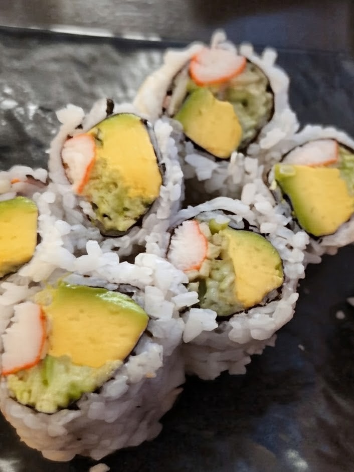 Shushi roll with giant green pieces of avocado. AKA California roll.