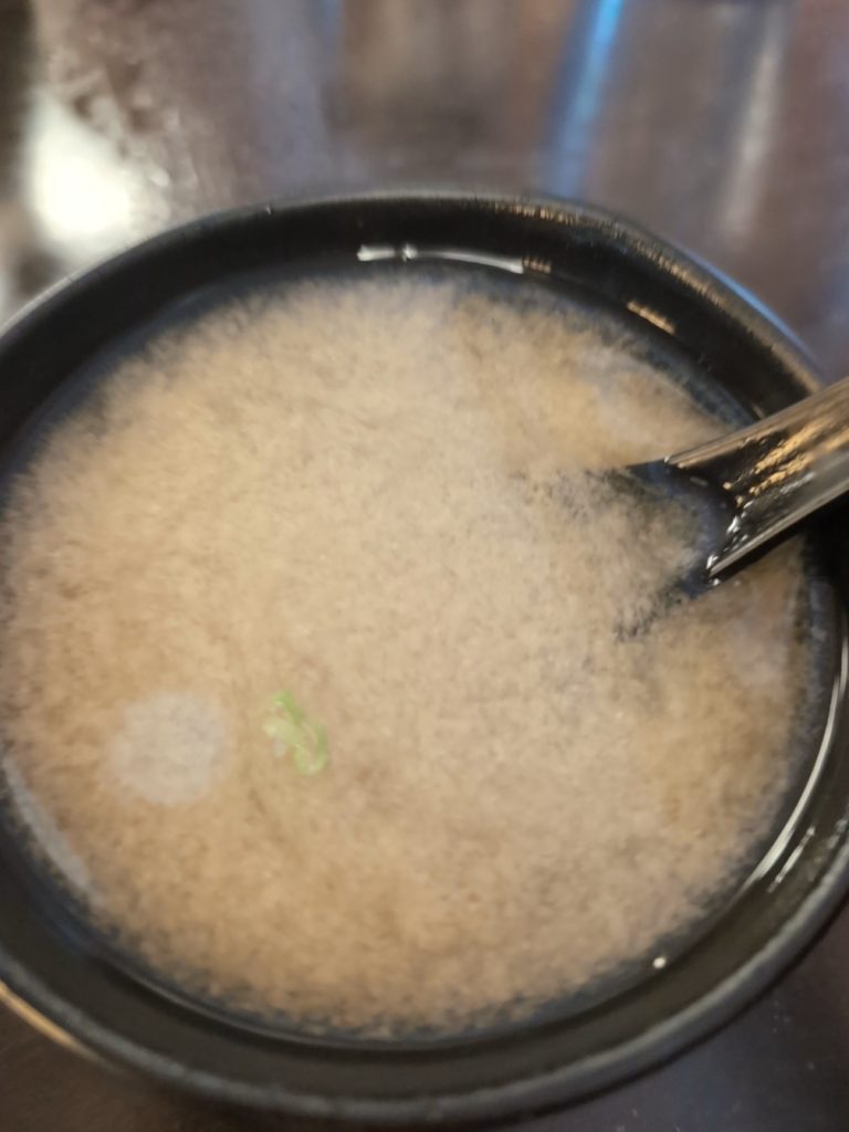 Off-white miso paste with onions in a miso soup.