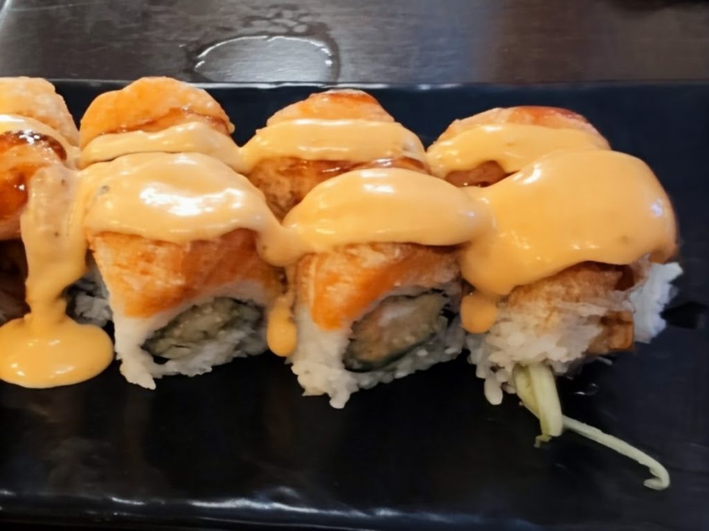 oozing orange spicy mayo topping a phoenix roll.